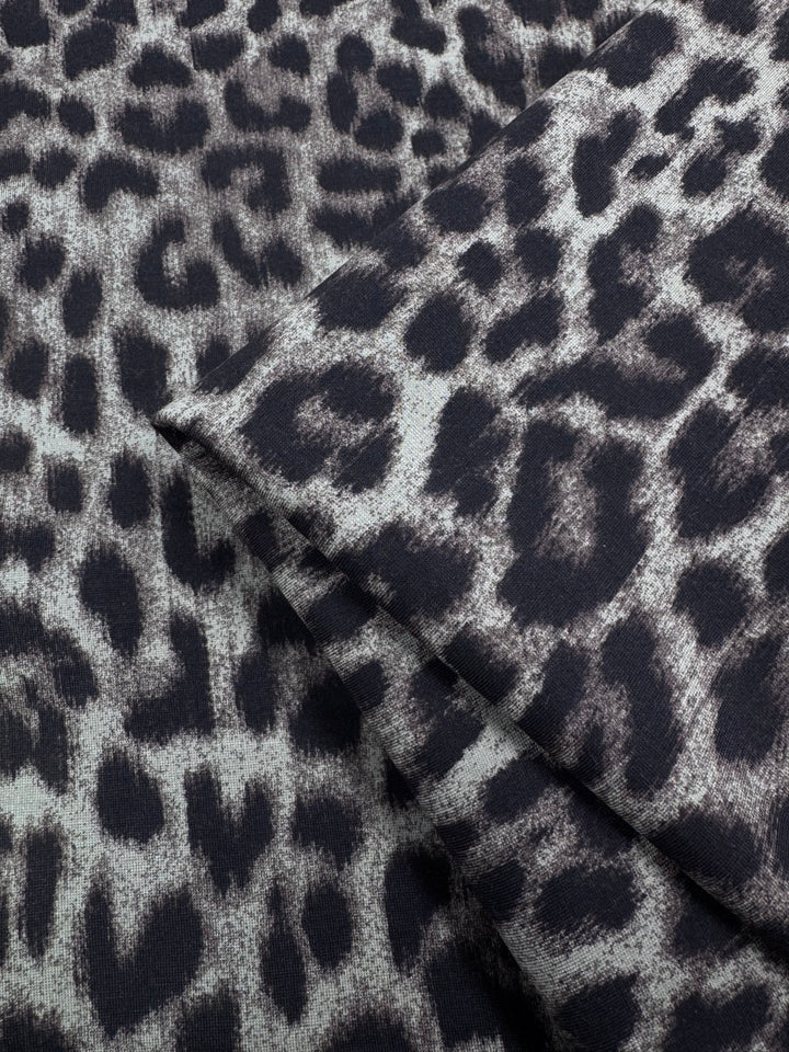 Close-up of Super Cheap Fabrics' Milano Ponte - 150cm, a heavyweight knit fabric with a black and gray leopard print, featuring irregular spots and a soft, textured finish.