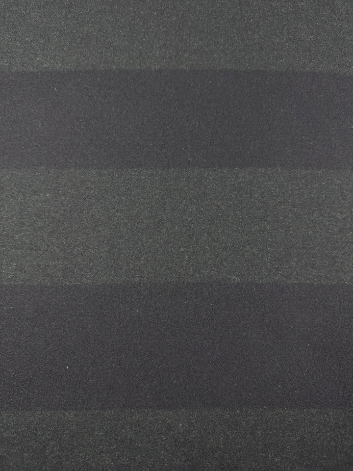 A close-up of a textured surface reveals two-tone black and khaki horizontal stripes. The material, Virgin Wool by Super Cheap Fabrics, measures 150cm wide and has a rough, grainy appearance akin to heavy-weight fabric or sandpaper.