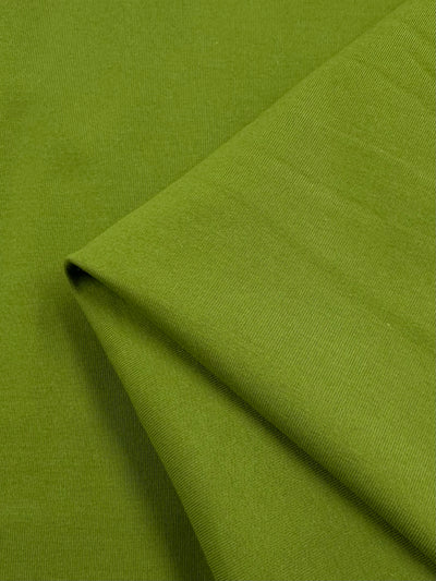 Close-up of a folded piece of vibrant Cotton Lycra - Spinach Green by Super Cheap Fabrics, highlighting its smooth texture and diagonal seam. The rich color and weave pattern, typical of bodycon dresses, add depth.