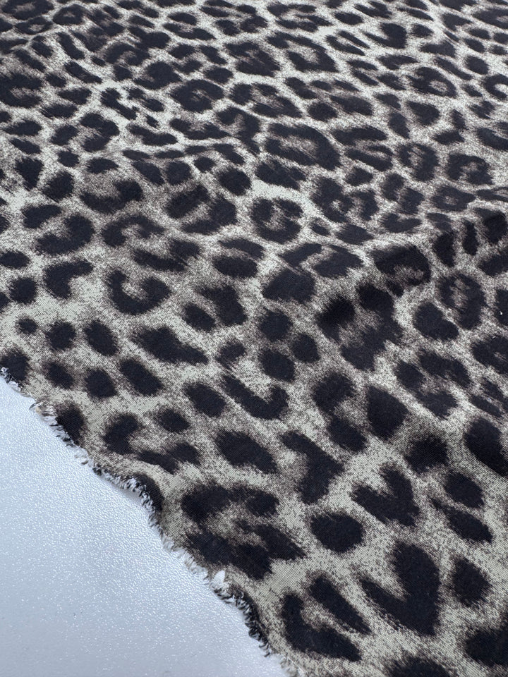 A close-up of Super Cheap Fabrics' Milano Ponte - 150cm shows the textured surface of its heavy weight knit with a black and brown leopard print and an unfinished, frayed edge on one side.