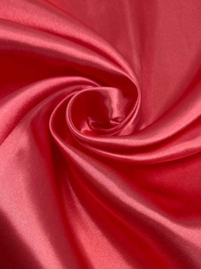 Super Cheap Fabrics' Satin - Coral Paradise - 150cm features smooth, shiny coral fabric with a luxurious appearance and elegant folds—ideal for stylish dresses or chic home décor accents.