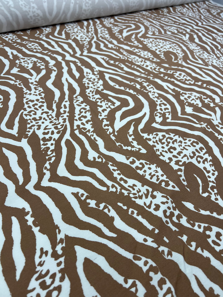 Close-up of a fabric laid flat, featuring a zebra stripe pattern in brown and white. This medium-weight fabric from Super Cheap Fabrics is known as "Printed Bengaline - Jungle Fusion - 150cm," and showcases bold, wavy stripes with occasional small dotted areas, giving it a dynamic and textured appearance—perfect for skirts, dresses, or pants made from stretch bengaline.
