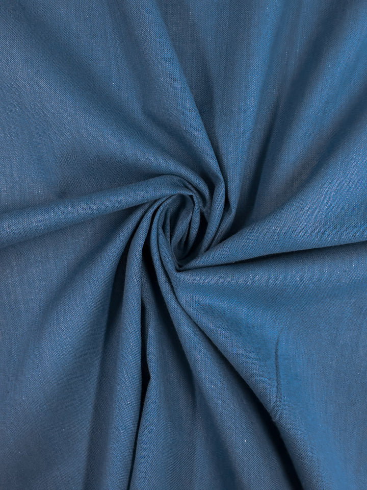 A close-up of Super Cheap Fabrics' Plain Cotton - Vallarta Blue - 108cm shows its fine texture, subtle folds, and delicate drape, highlighting the lightweight quality of this 100% cotton fabric.