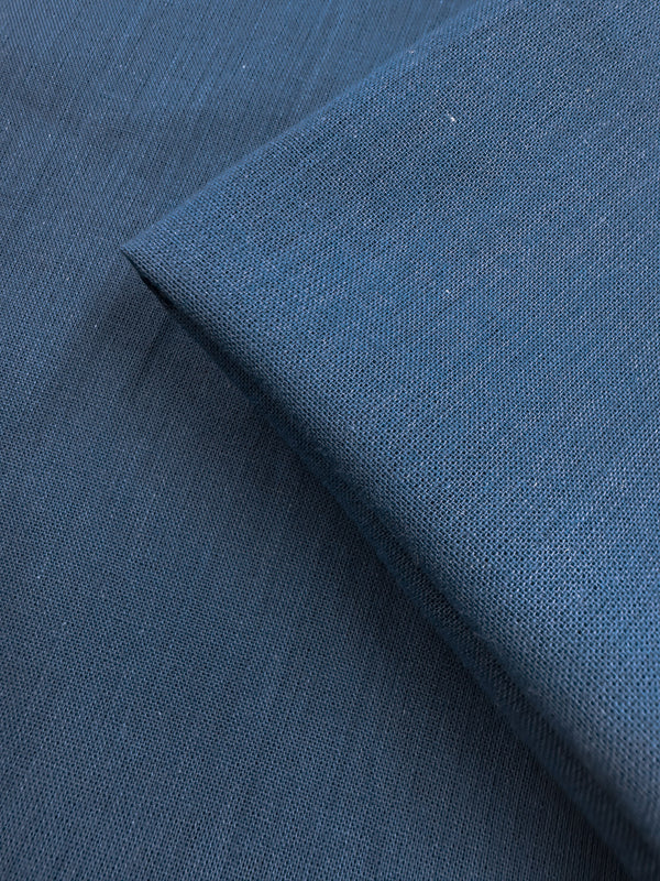 A close-up of two overlapping pieces of Super Cheap Fabrics' Plain Cotton - Vallarta Blue - 108cm shows fine threads, a subtle woven texture, and soft, smooth 100% cotton fabric with consistent color.