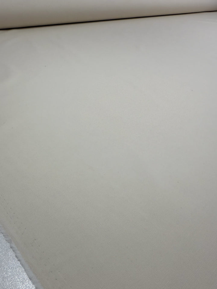 A close-up of Super Cheap Fabrics' Stretch Cotton - Antique White (147cm), laid flat to highlight its smooth, slightly textured 97% cotton surface and lightweight feel.