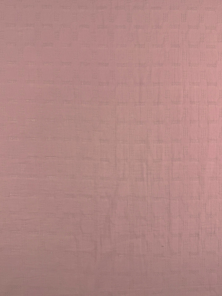A close-up of Super Cheap Fabrics' Textured Cotton - Misty Rose (140cm), a light pink lightweight cotton with a subtle, repeating rectangular woven pattern.