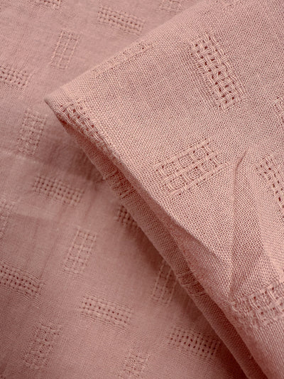 Close-up of Super Cheap Fabrics’ Textured Cotton - Misty Rose (140cm): lightweight cotton in light pink, showcasing a clear grid-like embroidered pattern with flat and folded sections for subtle geometric texture.
