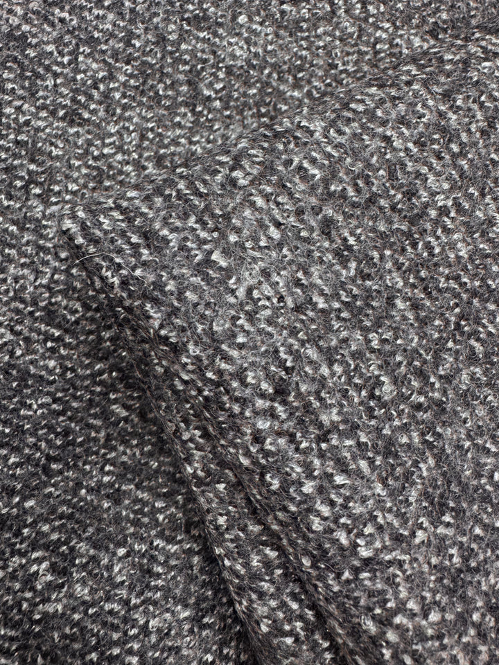 A close-up of Super Cheap Fabrics' Boiled Wool - Lamé Charcoal Marle - 150cm shows its softly bumpy, textured gray boucle pattern. The thick weave and subtle color variations enhance the heavy weight fabric's look.