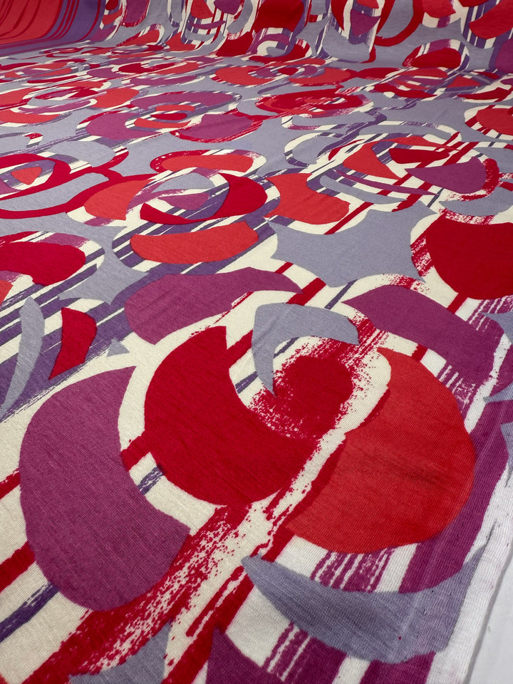 The Viscose Knit - Abstract Striped Geo (150cm) from Super Cheap Fabrics features a bold, breathable stretch fabric with overlapping red, purple, and gray shapes plus white and red stripes—ideal for summer projects.