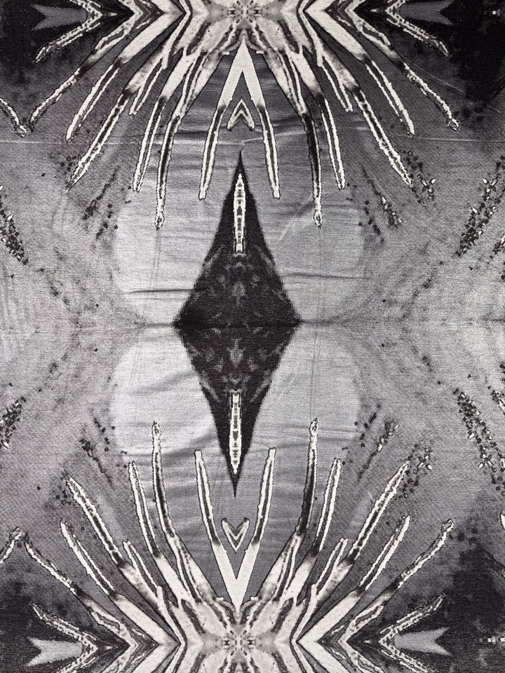 The Viscose Knit - Cosmic Burst by Super Cheap Fabrics features an abstract black and white symmetrical pattern with radiating lines and mirrored diamonds, ideal for breathable summer wear or soft stretch projects. Width: 145cm.