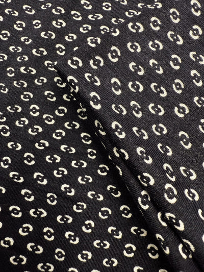 Close-up of Super Cheap Fabrics' Viscose Knit - Micro Dot (145cm), a black, medium-weight stretch fabric with a repeating pattern of small cream micro dots and a visible fold.
