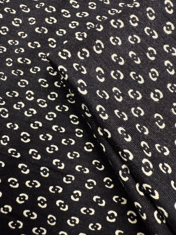 Close-up of Super Cheap Fabrics' Viscose Knit - Micro Dot (145cm), a black, medium-weight stretch fabric with a repeating pattern of small cream micro dots and a visible fold.