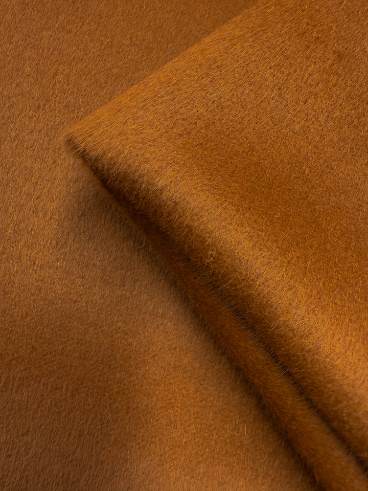 Close-up of Super Cheap Fabrics' Wool Cashmere in Roasted Pecan (150cm): luxurious, brown-orange fabric with a fuzzy texture, gentle folds, and a smooth, velvety finish.