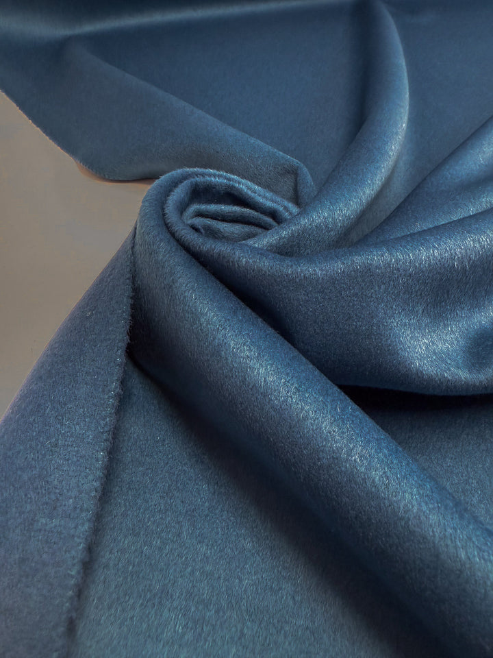A close-up of Wool Cashmere - Blue Steel by Super Cheap Fabrics shows its smooth, shiny surface and soft texture, loosely folded to highlight the luxurious sheen and fluid drape.