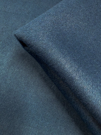 A close-up of Super Cheap Fabrics' Wool Cashmere - Blue Steel (150cm), showcasing its dark blue, heavyweight wool with a soft, fuzzy texture and subtle color variations in the light.