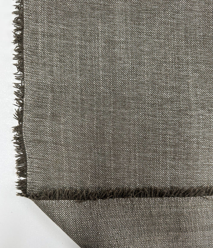 A diagonal close-up of Super Cheap Fabrics' Shitake Upholstery (142cm) showcases its textured gray fabric with fringed edges against a white background, highlighting its plain weave pattern and frayed details, ideal for a modern minimalist look.