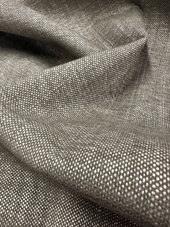 Close-up of textured gray "Upholstery - Shitake - 142cm" by Super Cheap Fabrics, ideal for modern minimalist decor. The fabric's woven pattern features subtle shade variations, showcasing its intricate texture and soft folds, perfect for upholstery.