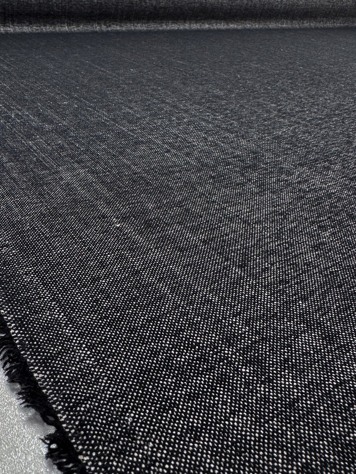 Close-up of Super Cheap Fabrics' Upholstery Tweed - Dresden Charcoal (146cm), a dark, textured woven fabric with visible fibers, frayed edge, and subtle sheen—ideal for durable upholstery projects.