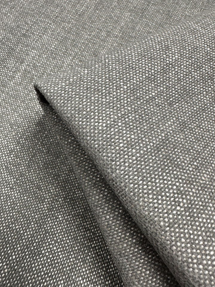 Close-up of the Dresden Warm Silver fabric by Super Cheap Fabrics, folded to reveal a thick, neatly layered structure with a simplistic design in a basket weave upholstery pattern.