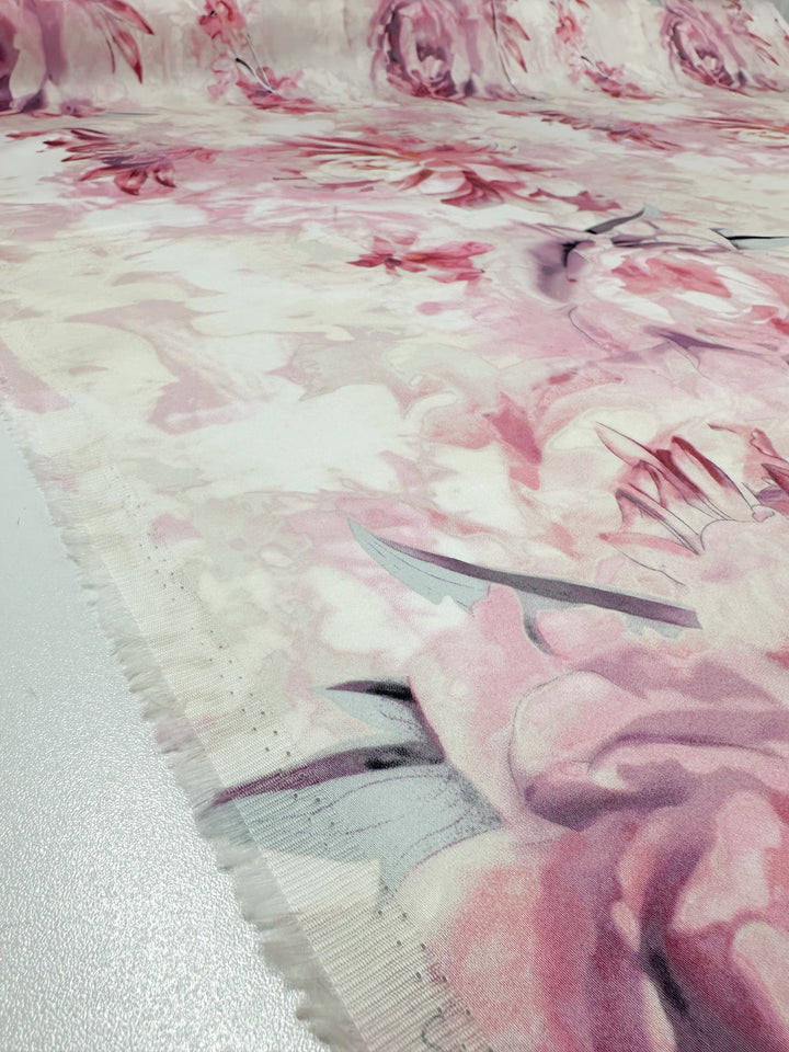 Close-up of Super Cheap Fabrics' Cotton Sateen - Mystic Garden features medium-weight sateen with pink floral designs blending into a light cotton background. The fabric, ideal for home décor, boasts soft abstract flowers covering most of its 125cm width, providing a delicate artistic look.