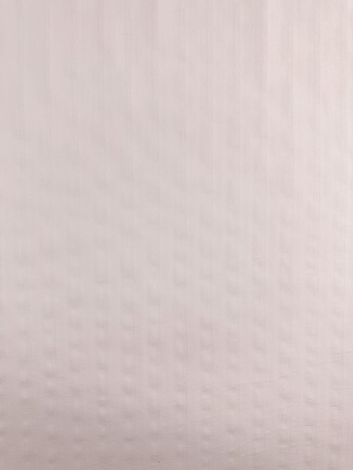 The silver pink Textured Cotton fabric from Super Cheap Fabrics features a vertical ridge pattern that evokes the softness of cotton, with light and shadow creating gentle depth akin to its delicate weave.