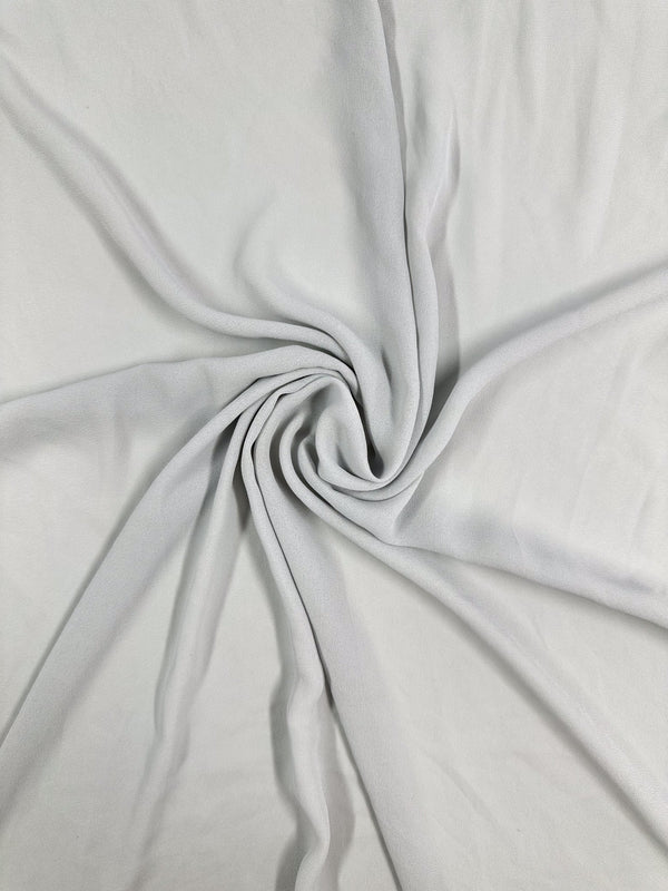 The Hi-Multi Chiffon - Oyster Mushroom from Super Cheap Fabrics is a light gray, lightweight fabric twisted into a spiral pattern, creating gathered folds that accentuate its soft, smooth texture—ideal for crafting floaty tops.