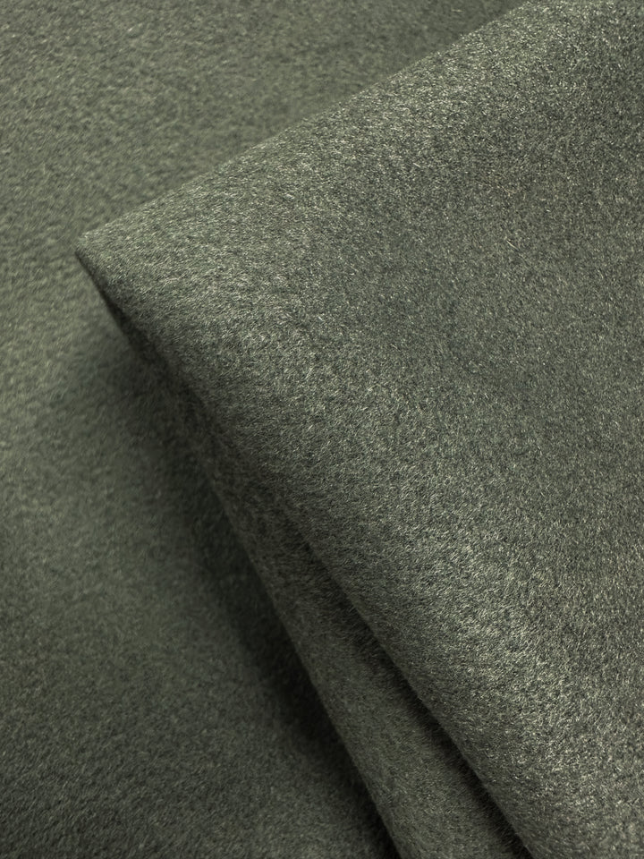 Close-up of overlapping pieces of Super Cheap Fabrics' Wool Cashmere in Agave Green (150cm), highlighting its luxurious softness and smooth, slightly fuzzy texture.