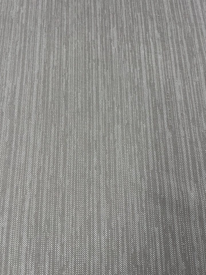 Close-up image of a grey, textured fabric with a subtle vertical and horizontal weave pattern, creating a slightly ribbed appearance. This durable fabric is perfect for furniture upholstery, offering a uniform color and an even, fine texture that complements any décor. Upholstery Twill - Natural - 147cm by Super Cheap Fabrics