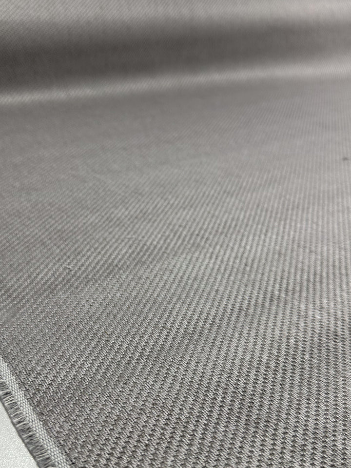 A close-up of the Twill Upholstery - Rex 370 - 150cm fabric by Super Cheap Fabrics, featuring soft gray textured material with a subtle diagonal pattern, displayed slightly out of focus and laid flat.