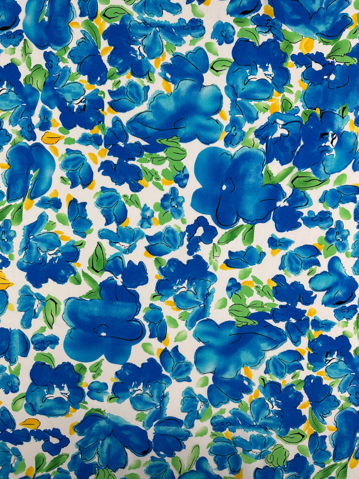 Azure Whispers by Super Cheap Fabrics features blue and turquoise watercolor flowers with green leaves and yellow accents on white rayon (145cm), perfect for eye-catching, designer floral projects.
