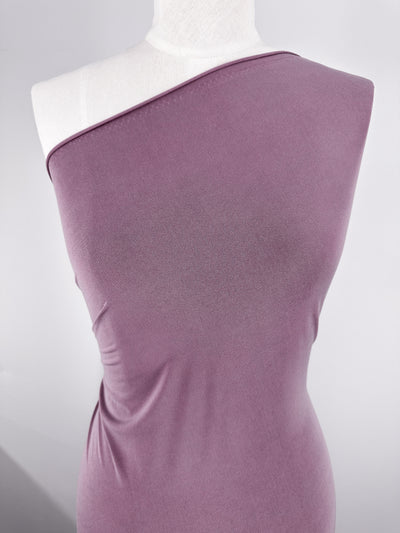 A dress form displays Super Cheap Fabrics' ITY Knit - Damson (150cm), a mauve, medium-weight polyester spandex. The fitted fabric highlights the mannequin’s shape with an exposed left shoulder and a plain, light background.