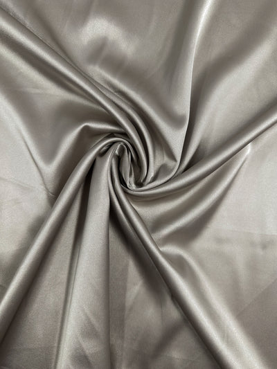 Satin Deluxe - Rock Ridge by Super Cheap Fabrics features a shiny silver-gray luxury fabric with a smooth texture, soft folds, and subtle sheen. Width: 150cm.