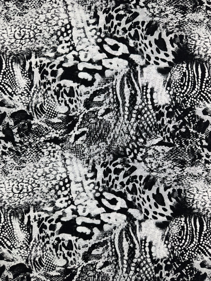 The Jacquard Bengaline - Survivor 145cm from Super Cheap Fabrics showcases an abstract animal print in black and white, blending leopard spots and snake scales on medium-weight stretch fabric. Its reversible design adds a visually dynamic, intricate appearance.