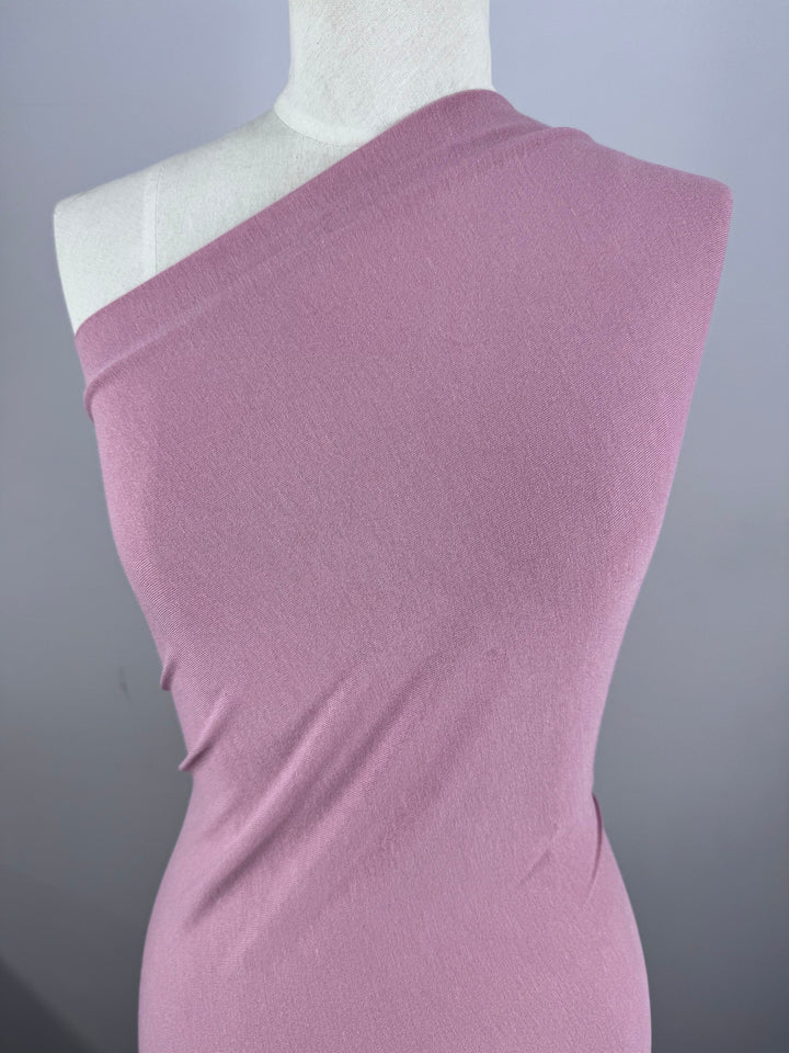 A mannequin displays a light pink, one-shoulder bodycon dress tailored from Super Cheap Fabrics' Cotton Lycra in Fox Glove (155cm), set against a plain gray backdrop.