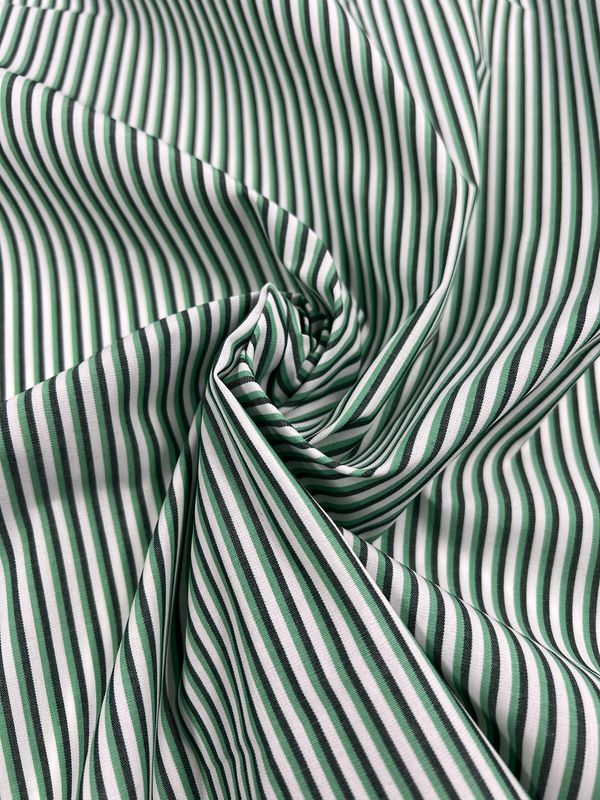A close-up of Shirting - Lizard - 150cm by Super Cheap Fabrics, featuring lightweight poly-cotton with green and black vertical stripes, gathered into soft folds.