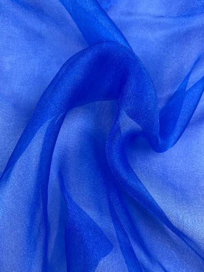 A close-up of Super Cheap Fabrics’ Organza - Royal - 150cm in blue, highlighting its smooth, sheer, and lightweight texture with delicate folds and translucence.