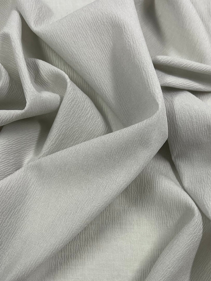 A close-up of Super Cheap Fabrics' Stretch Crinkle - Mirage Gray (140cm), a soft polyester with subtle wavy texture. The medium weight fabric is gently draped and folded, showing natural creases and shadows.